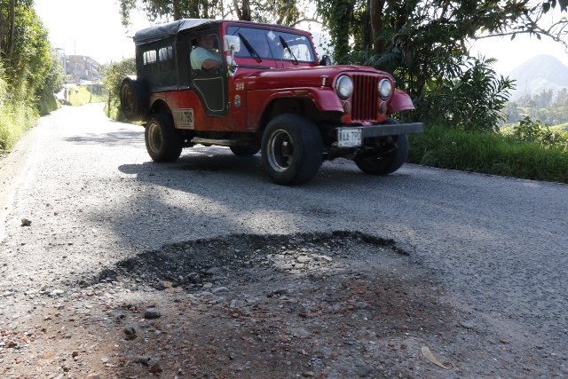 Los carros deben esquivar los rotos para evitar accidentes, pero se arriesgan invadiendo el carril contrario.