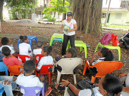 La profesora y promotora de lectura Viviana Vanegas lee frente a varios niños en la Bicibiblioteca del Saber.