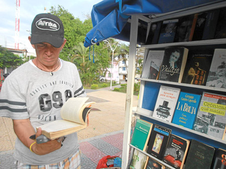 Juan Antonio García lee un libro junto al vehículo en el que lleva decenas de textos.