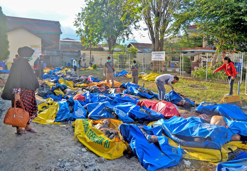 Familiares buscan a sus seres queridos en bolsas de cadáveres en una Estación de Policía en Palu.