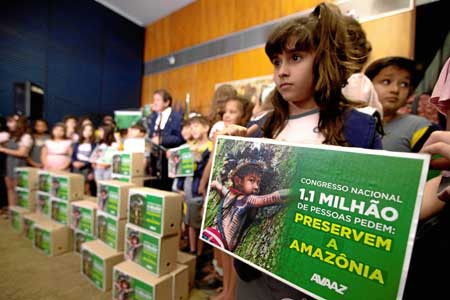 Una niña posa con un cartel en el que se lee: Congreso nacional 1.1 millón de personas piden: Preservar la Amazonía durante la e