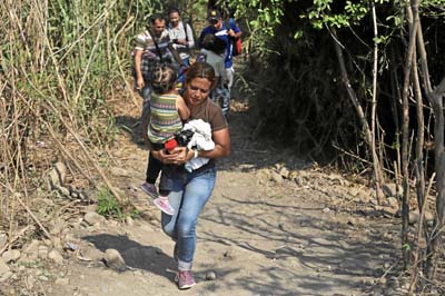 Con sus hijos en brazos cruzan por las trochas a Colombia en busca de medicinas y comida. 