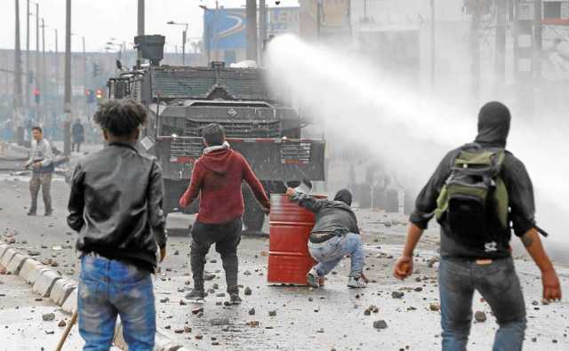 Una tanqueta de la policía antidisturbios enfrenta a un grupo de manifestantes este viernes, en un sector de Patio Bonito, sur d