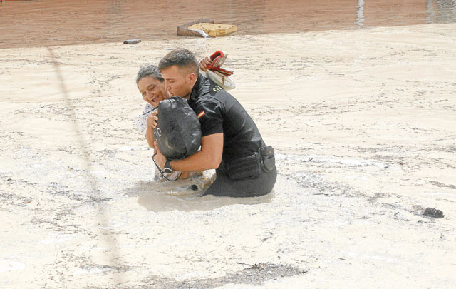 Un Policía rescata a una anciana que había quedado atrapada tras el rompimiento de un muro que contenía las aguas de un río.