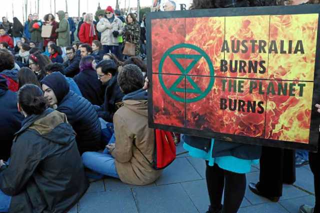 Jóvenes ecologistas de Fridays for Future muestran un cartel con el mensaje Australia arde, el planeta arde, frente a la embajad