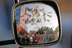 Reflejo de los manifestantes en un retrovisor roto durante la marcha Bienvenidos al infierno.