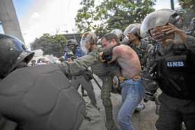 Miembros de la Guardia Nacional Bolivariana detienen a un hombre durante una protesta en la huelga general convocada por la opos
