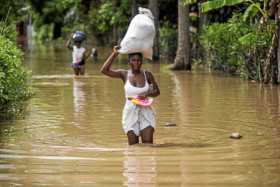 Foto | Efe | LA PATRIA  Una mujer carga algunas pertenencias mientras camina por una calle inundada tras el paso de Irma en el t