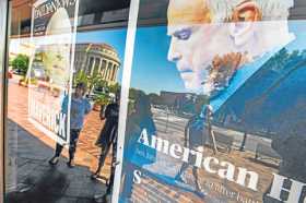 Los peatones se reflejan en la página principal de Fayetteville Observer y NY Daily News, que conmemoran al senador republicano 