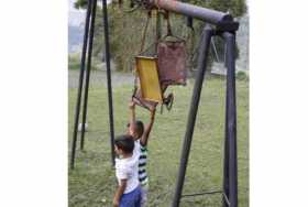 Niños del Bajo Tablazo intentan jugar con lo que queda de un columpio de parque, porque la cancha también está deteriorada y aba