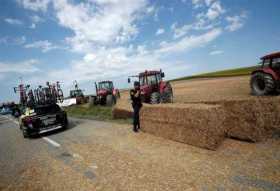 Agentes de policía despejan una carretera bloqueada por una manifestación de agricultores durante la decimosexta etapa del Tour 