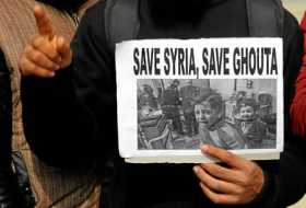 Un miembro del Foro Global de Investigación del Islam sostiene una pancarta en la que aparecen unos niños sirios en los bombarde