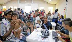 Cientos de familias venezolanas que huyeron de su país por la crisis económica y política hacen fila para reclamar los bonos ali