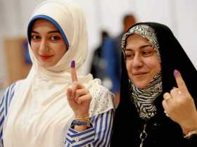 Dos mujeres iraquíes muestran los dedos manchados de tinta tras votar para las elecciones parlamentarias