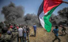 Manifestantes corren para protegerse del gas lacrimógeno lanzado por soldados israelíes durante unas protestas en la frontera de