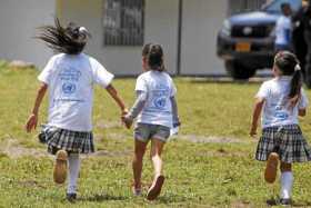 Unas niñas vestidas con camisetas de la ONU por el Día Internacional de la Paz corren en la vereda Llano Grande, en el municipio