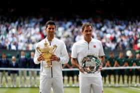 El serbio Novak Djokovic (i) con el trofeo del campeonato después de derrotar al suizo Roger Federer en la final masculina del C