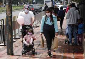 Una familia protegida con tapabocas camina este sábado en Bogotá. Colombia entró en una fase crítica de la pandemia del coronavi