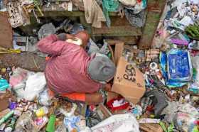 Un hombre escarba en la basura junto a una caja de Los Comités Locales de Abastecimiento y Producción (CLAP), en Caracas (Venezu