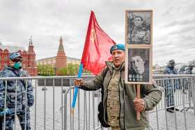 Un hombre ruso sostiene la bandera roja y los retratos de sus familiares veteranos de la Segunda Guerra Mundial cerca de la Plaz