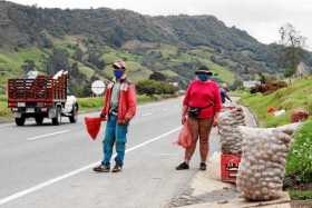 Foto | EFE | LA PATRIA A lado y lado de la carretera, los campesinos han puesto las hileras de bultos a la espera de que los via