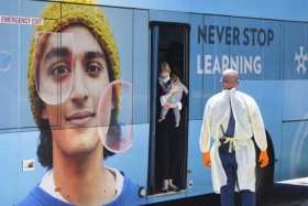 Una mujer que lleva en brazos a su bebé baja de un autobús a su llegada para la cuarentena obligatoria de 14 días en el hotel Pa