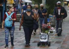 Personas observan un robot que reparte flores en las calles de Medellín (Colombia). La Feria de las Flores de Medellín se realiz