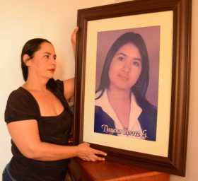 Gloria sosteniendo un cuadro de su hija.