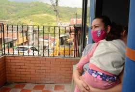 Sandra carga a su hija, de dos años, en la puerta de su casa.