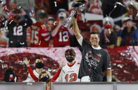 El mariscal de campo de los Tampa Bay Buccaneers, Tom Brady, celebra con el Trofeo Vince Lombardi mientras está de pie con los n