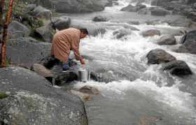 Un hombre de Cachemira llena su balde con agua de un arroyo en las afueras de Srinagar, la capital de verano de Cachemira.