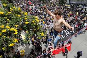 Un hombre camina sobre una cuerda con el nombre de Lucas pintado en su pecho, uno de los manifestantes que murió durante las pro