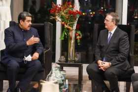 El presidente de Venezuela, Nicolás Maduro (i), mientras conversa con el secretario de Relaciones Exteriores de México, Marcelo 
