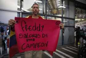 Un aficionado sostiene un cartel de apoyo al exfutbolista Freddy Rincón, a las afueras de la clínica Imbanaco donde se encuentra