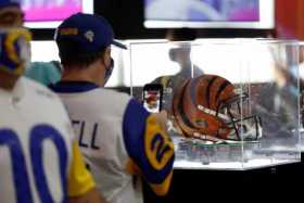 Un fanático de Los Angeles Rams toma una foto de un casco decorado de los Cincinnati Bengals en la experiencia del Super Bowl de