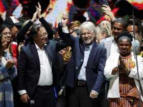 El presidente electo, Gustavo Petro, alza la mano del exalcalde de Bogotá Antanas Mockus (c) durante su primer discurso luego de