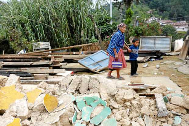Una anciana camina, junto a su nieto por los escombros de su casa, que fue destruida durante el terremoto que tuvo epicentro en 