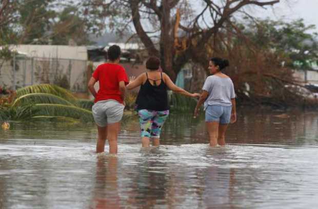 Mujeres cruzan una calle inundada tras el paso del huracán María
