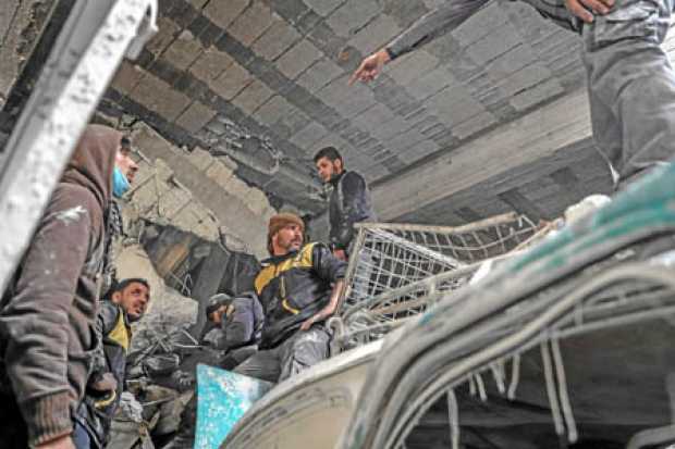 Voluntarios de los Cascos Blancos y civiles buscan sobrevivientes entre los escombros, después de los bombardeos en Guta Orienta