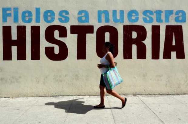  Una mujer pasa junto a un cartel alusivo a la revolución cubana.