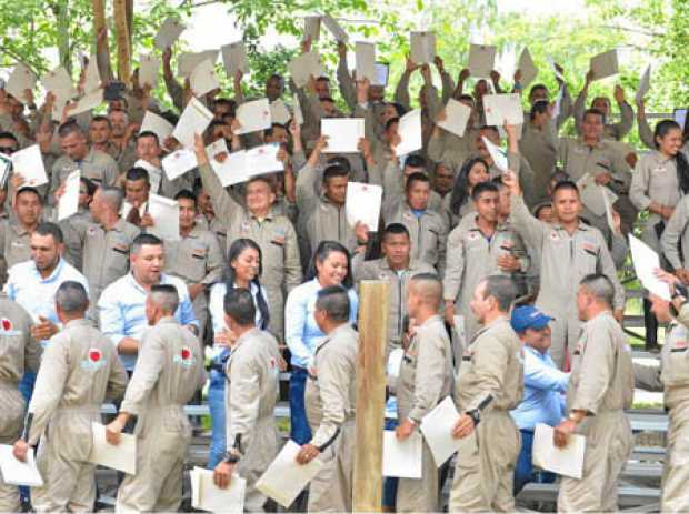 Los excombatientes elevando el certificado que los acredita como técnicos agropecuarios.