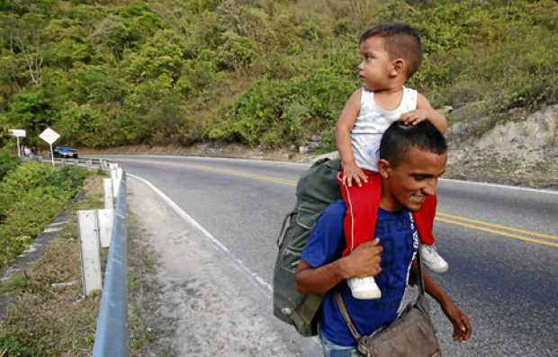 Foto | EFE | LA PATRIA   Un padre venezolano carga a su hijo mientras recorre la vía hacía Bucaramanga desde Cúcuta. 