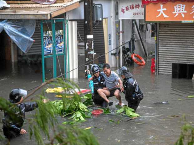 Foto | Efe | LA PATRIA  Agentes de la Policía rescatan a un hombre de una calle inundada durante el tifón Mangkhut en Lei Yu Mun