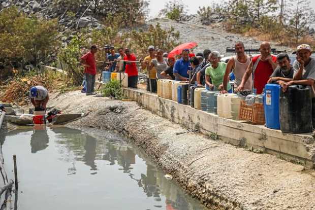 Las filas ante las fuentes de agua son iguales para chavistas y no chavistas. En las zonas populares de Caracas los rostros cans