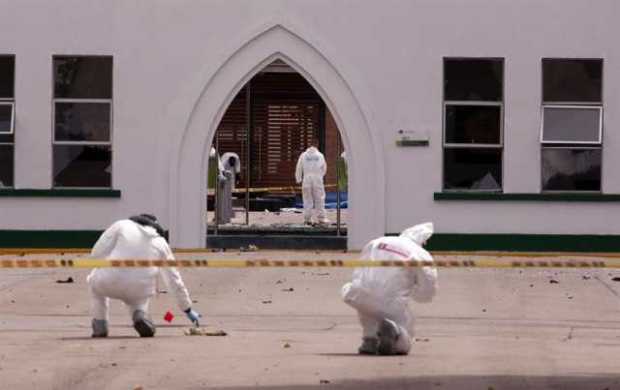 Peritos forenses inspeccionan el lugar donde un carro bomba causó una explosión este jueves en la Escuela General Santander de l