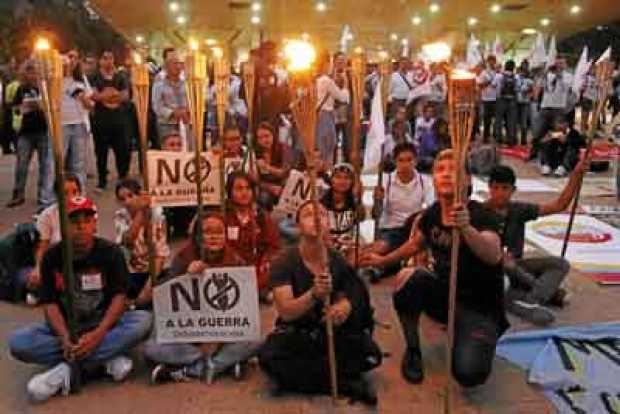 Manifestantes sostienen carteles y encienden antorchas durante un plantón a favor de la JEP en Medellín.