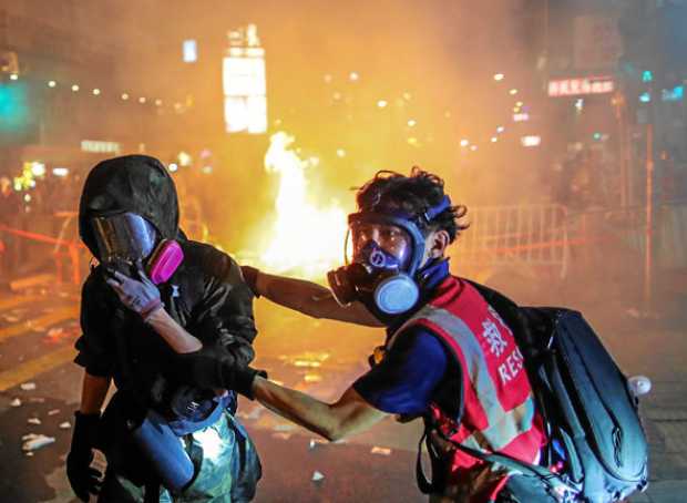 Manifestantes que protestan contra el Gobierno en Hong Kong (China) se protegen del gas lacrimógeno lanzado por la Policía. 
