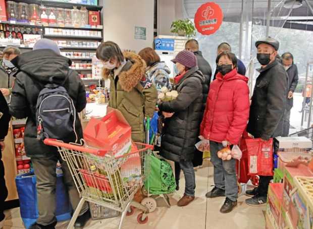 Los residentes hacen cola para comprar comestibles en un mercado, a medida que los precios de los alimentos se disparan debido a