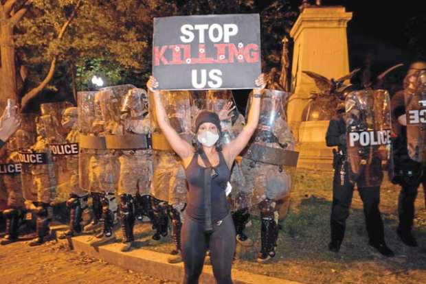 Una manifestante con una pancarta en la que se puede leer "Dejad de matarnos" durante las manifestaciones por el asesinato de Ge