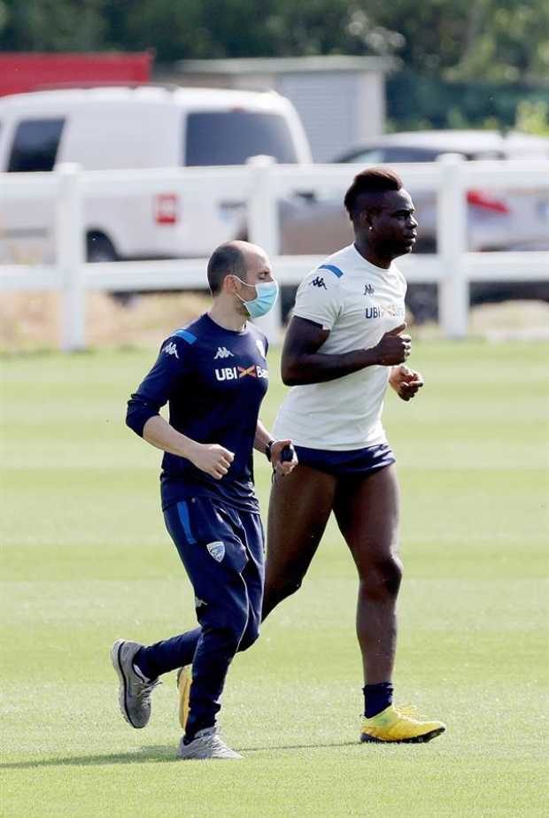 El delantero Mario Balotelli (d) del club italiano de la Serie A Brescia Calcio y el preparador físico Stefano Cellio realizan u